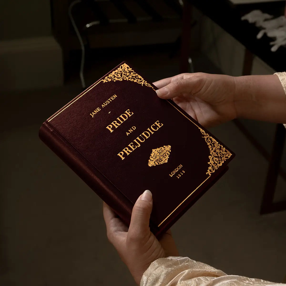 A woman in regency attire holding the Pride and Prejudice Book Clutch Burgundy