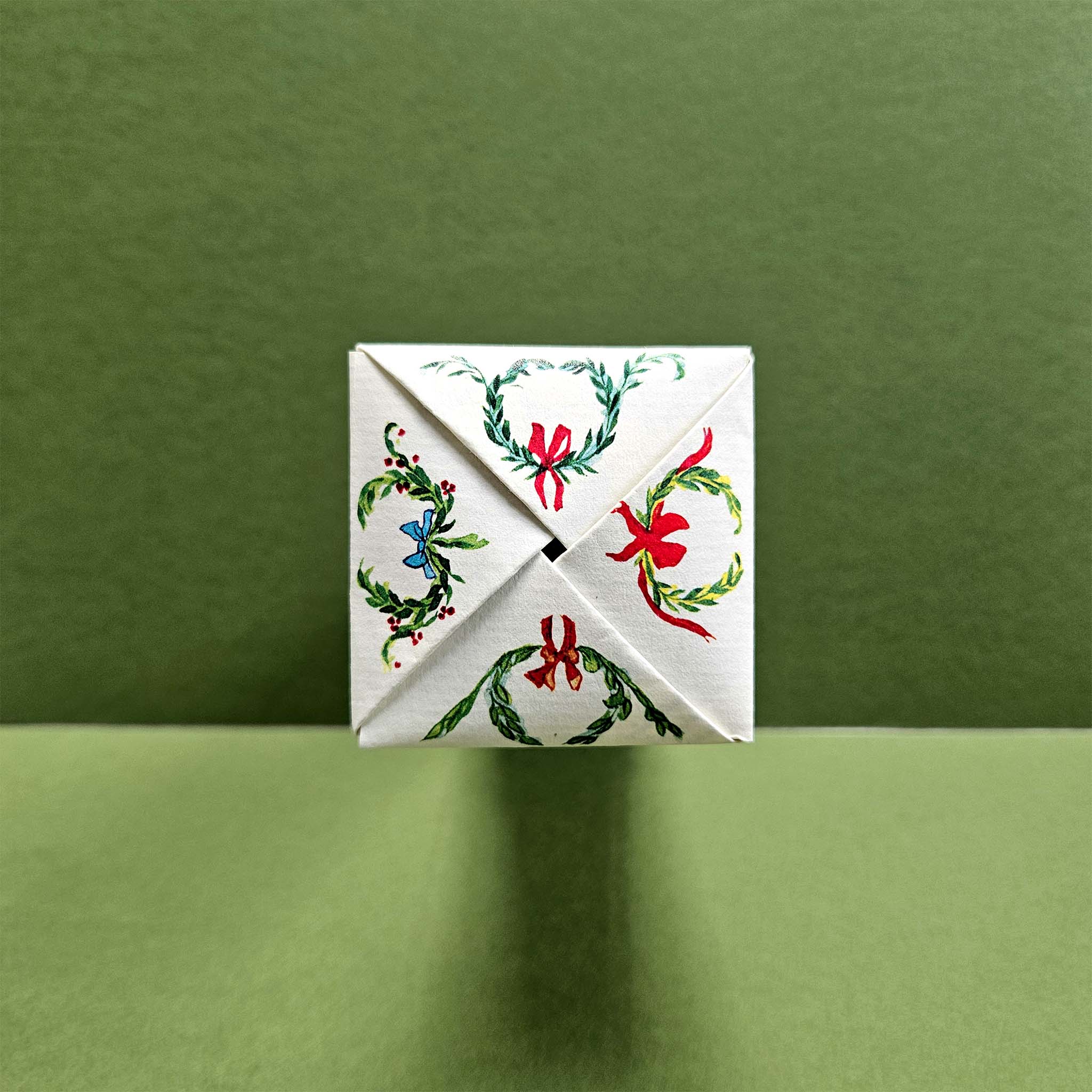 Decorative box with Christmas wreath and bow design on a green background