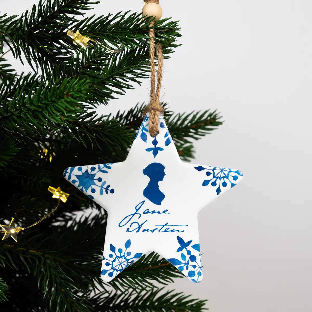 Jane Austen themed star shaped blue and white ceramic christmas decoration, hanging from a Christmas tree