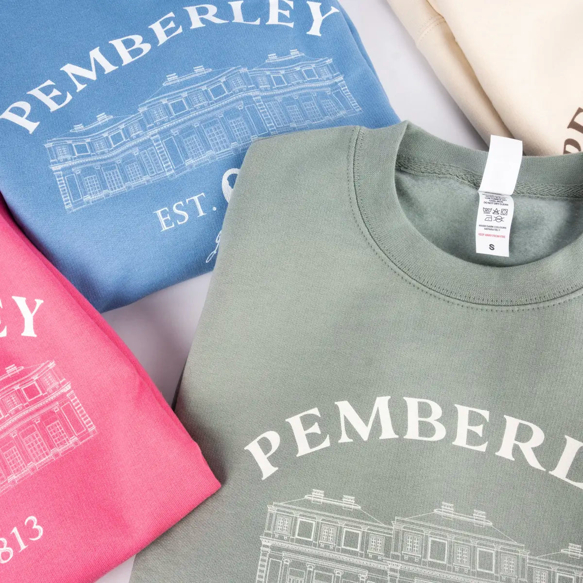 collection of different coloured Jane Austen Pemberley sweaters in blue, red, and green