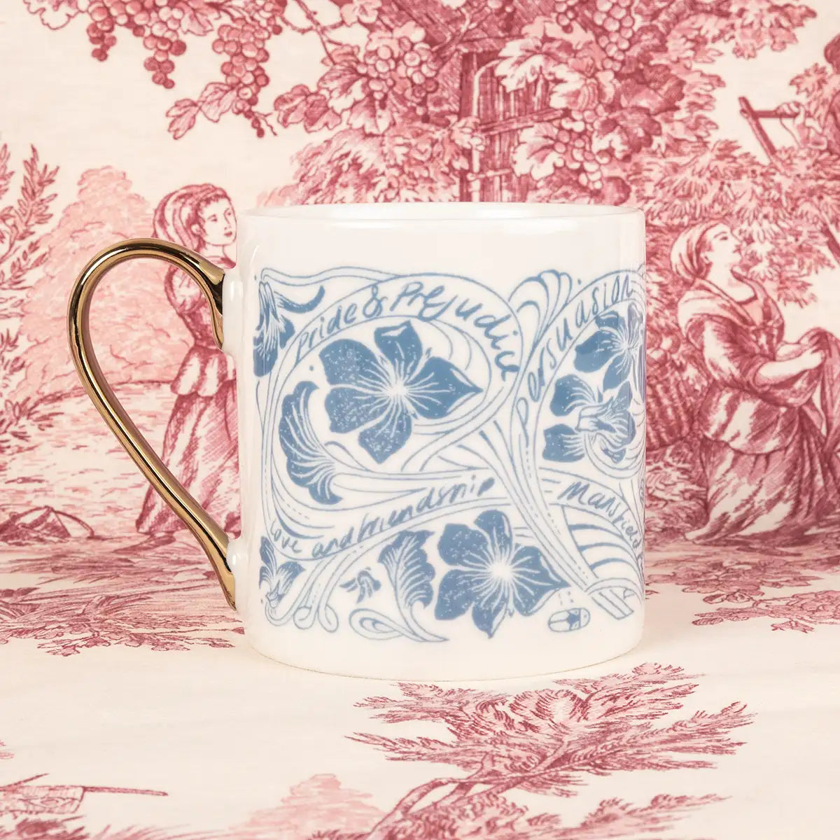 Cream mug decorated in swirling blue flower illustrations and the names of Jane Austen's novels. Gold handle.