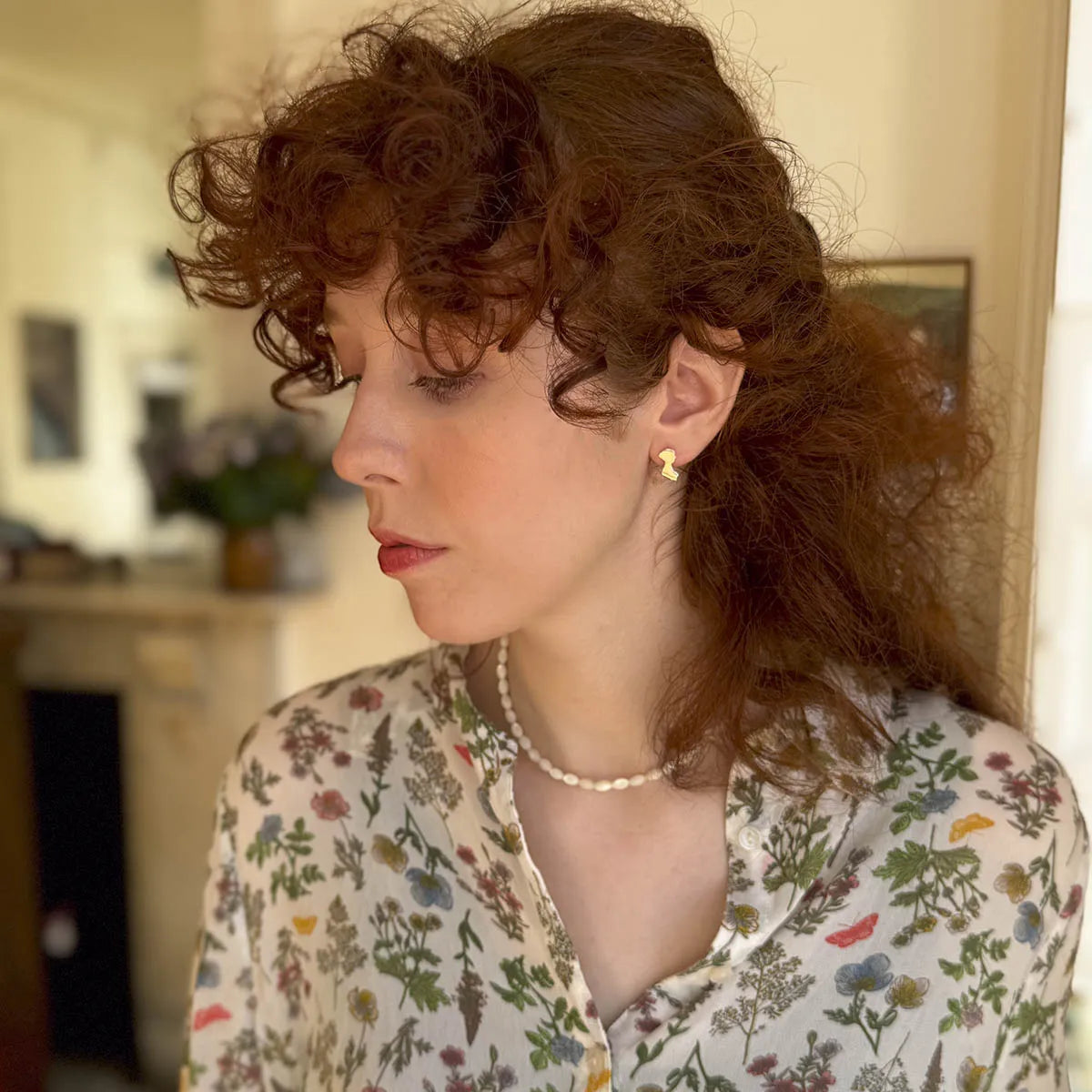 Gold Plated earrings in the shape of jane Austen's silhouette on a womens ear