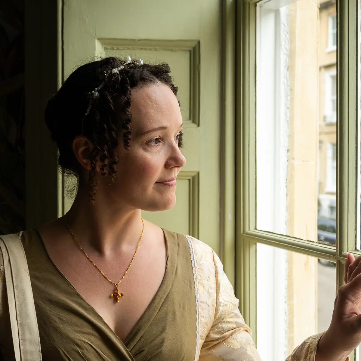 woman in regency attire looking out of a window