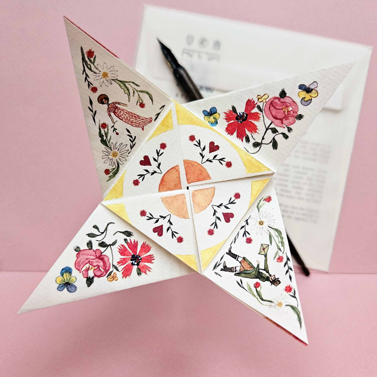 Decorative paper star with floral designs on a pink background