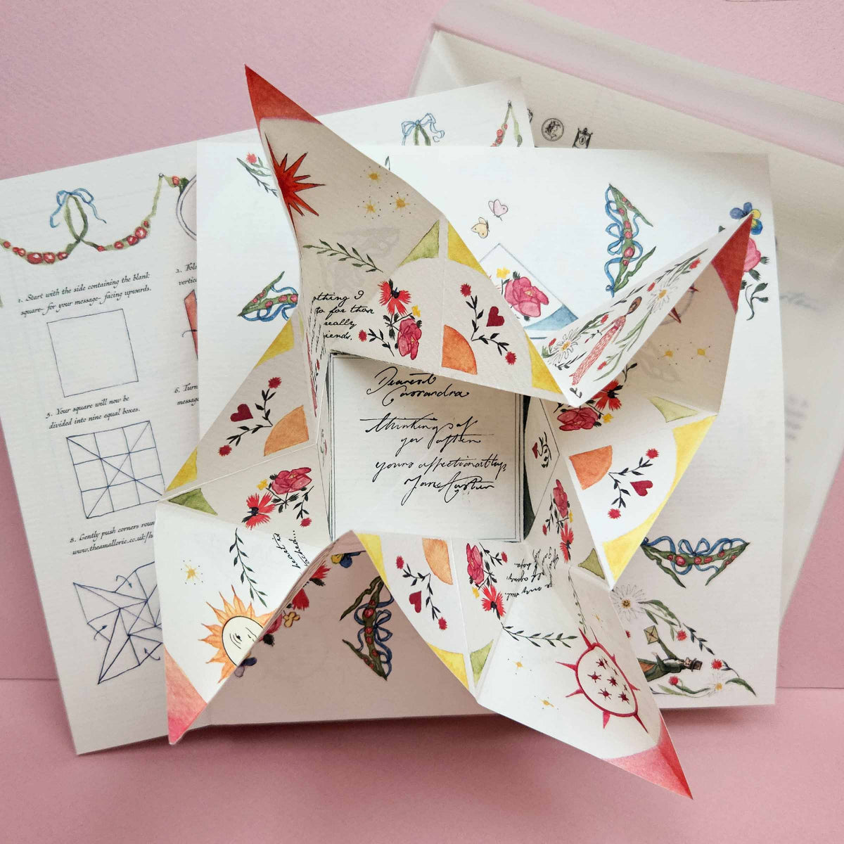 Colorful paper windmill with decorative patterns on a pink background