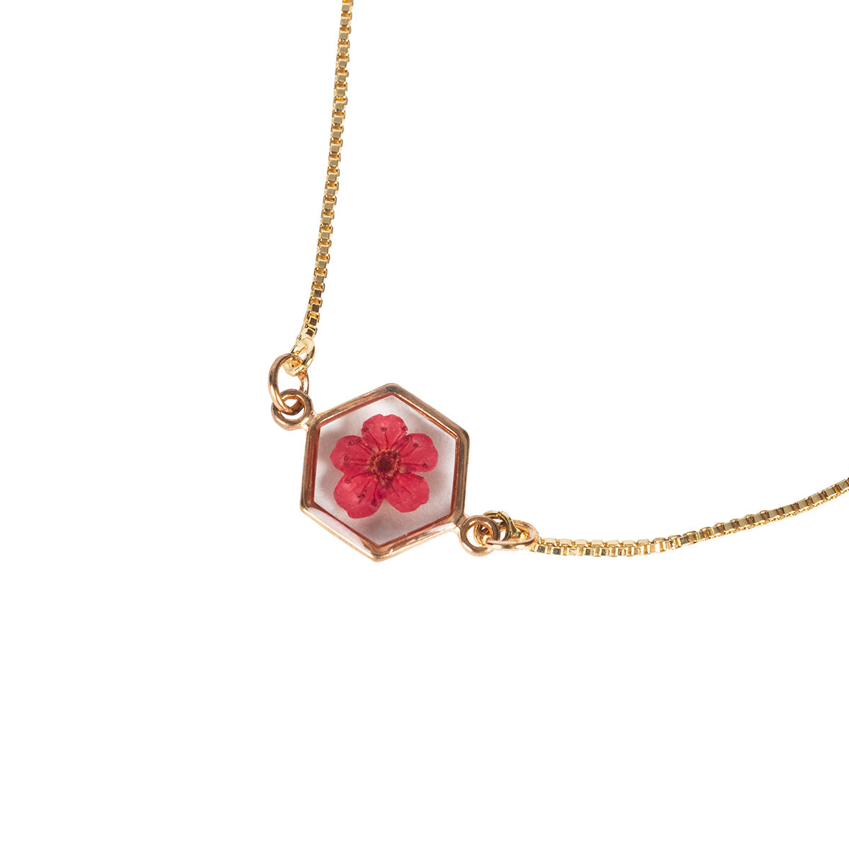Closeup of a Red Flower Bracelet with gold chain and hexagon shaped frame with a red pressed flower set in resin