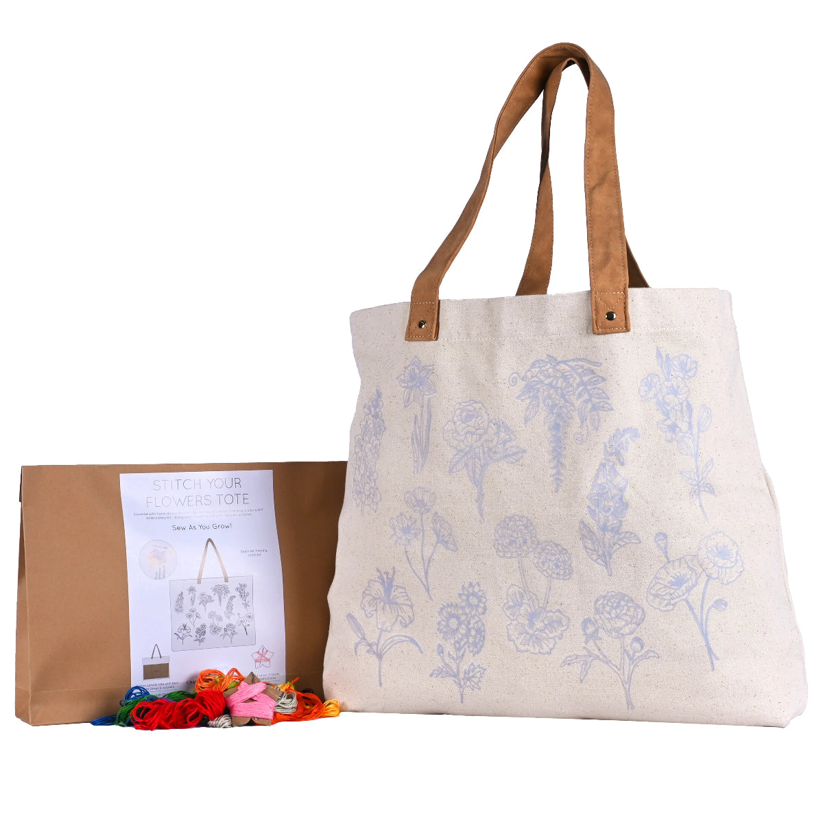 A tote bag with a floral embroidery pattern outlined on the front, accompanied by a packaging bag and colourful embroidery threads.