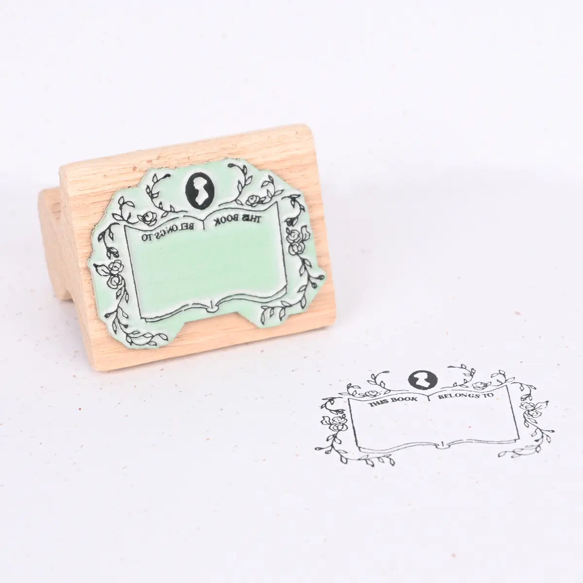 Wooden stamp with example showing a Jane Austen logo, floral framing and text "This book belongs to"