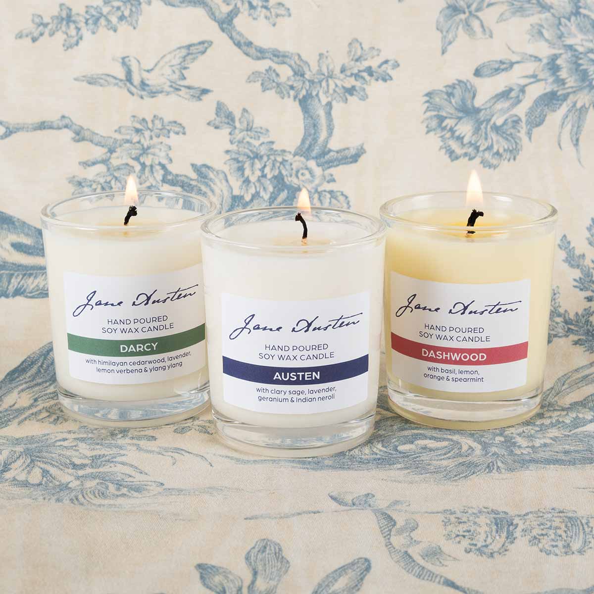 Three lit candles on a patterened background: Darcy, Austen and Dashwood.