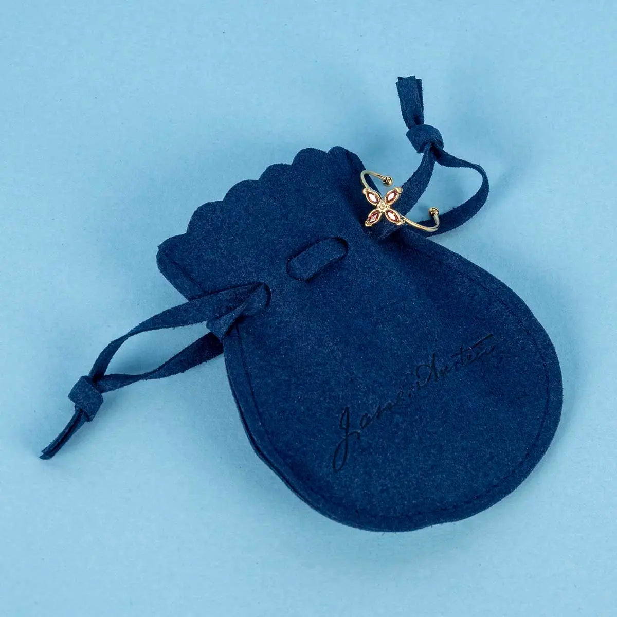 Elizabeth bennet themed garnet ring on a blue felt drawstring bag embossed with jane austen's signature