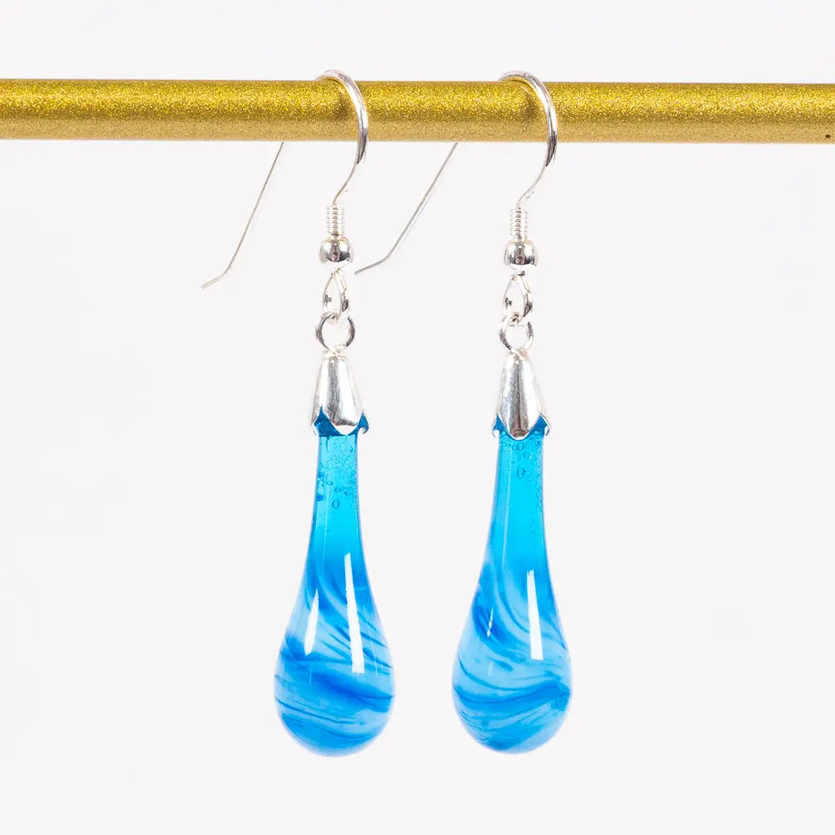 blue glass drop earrings hanging from a gold bar against a white background