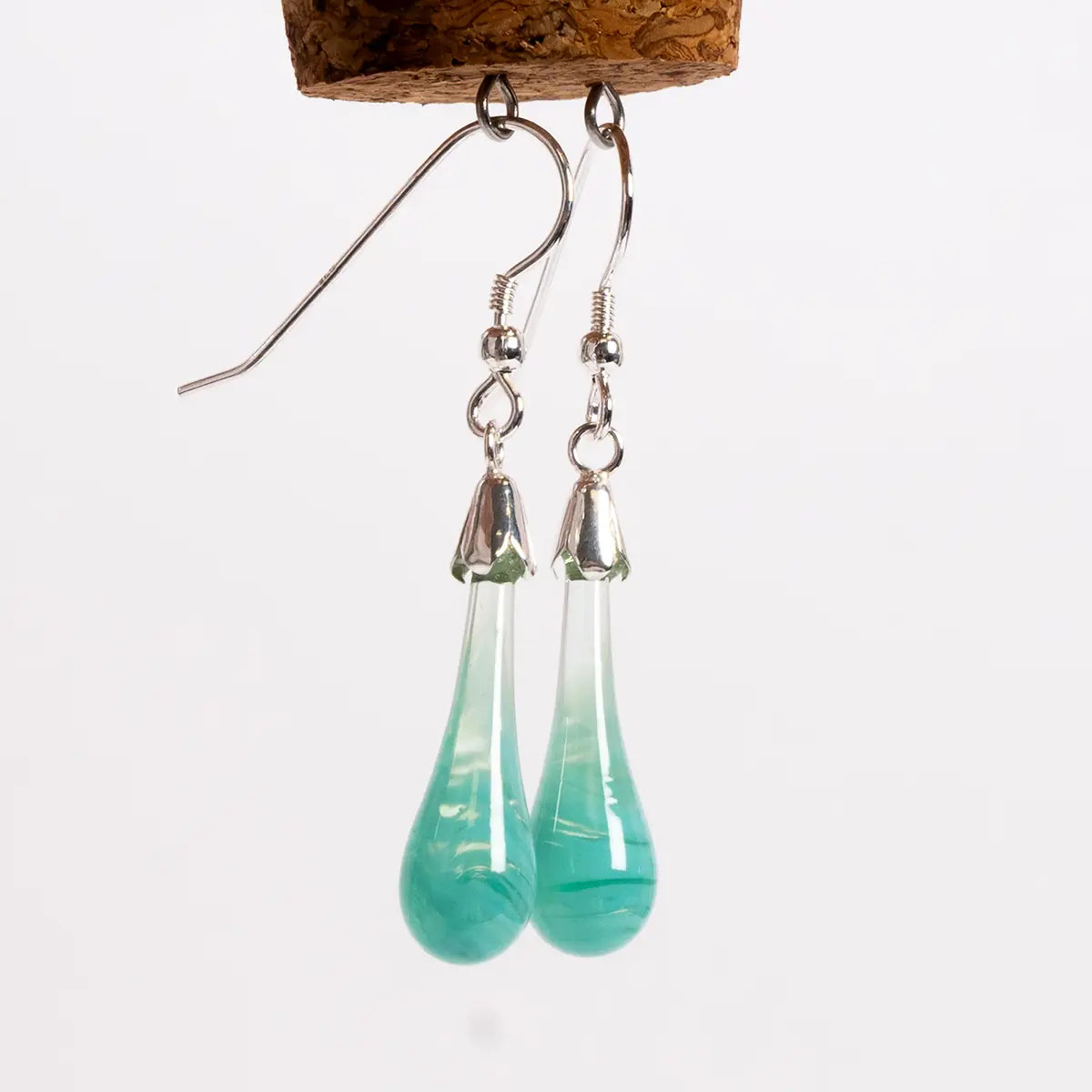 glass drop earrings with silver details hanging from a cork with loops
