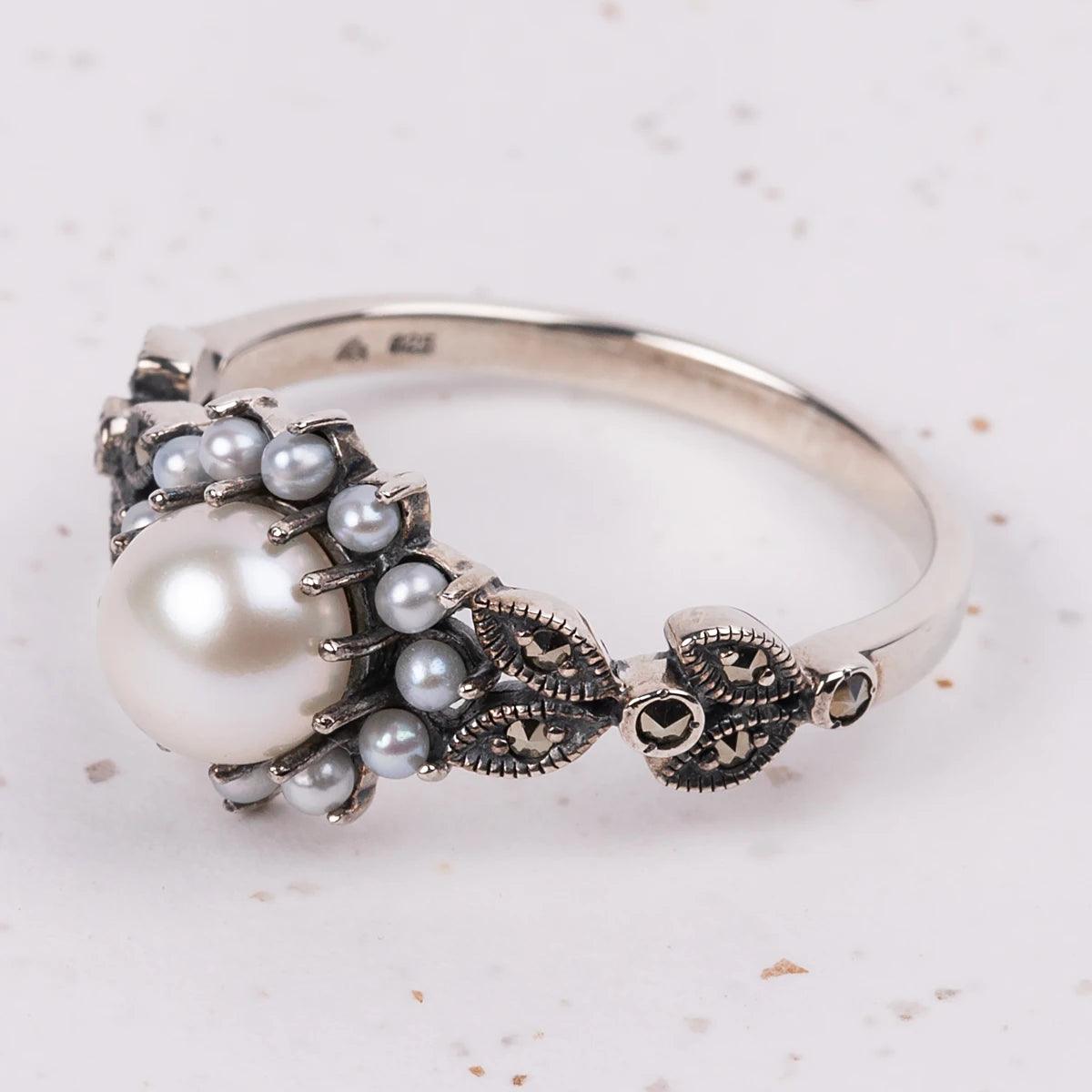Closeup of a Silver, Marcasite and Pearl ring surrounded by smaller pearls