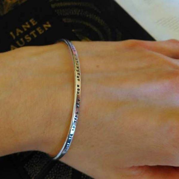 Bracelet on arm with words "You must allow me to tell you how ardently I admire and love you"