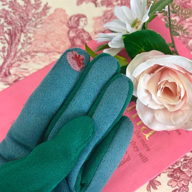 Green cotton gloves with pink, green, blue, and yelllow embroidered design on it, reminiscent of regency embroidery designs