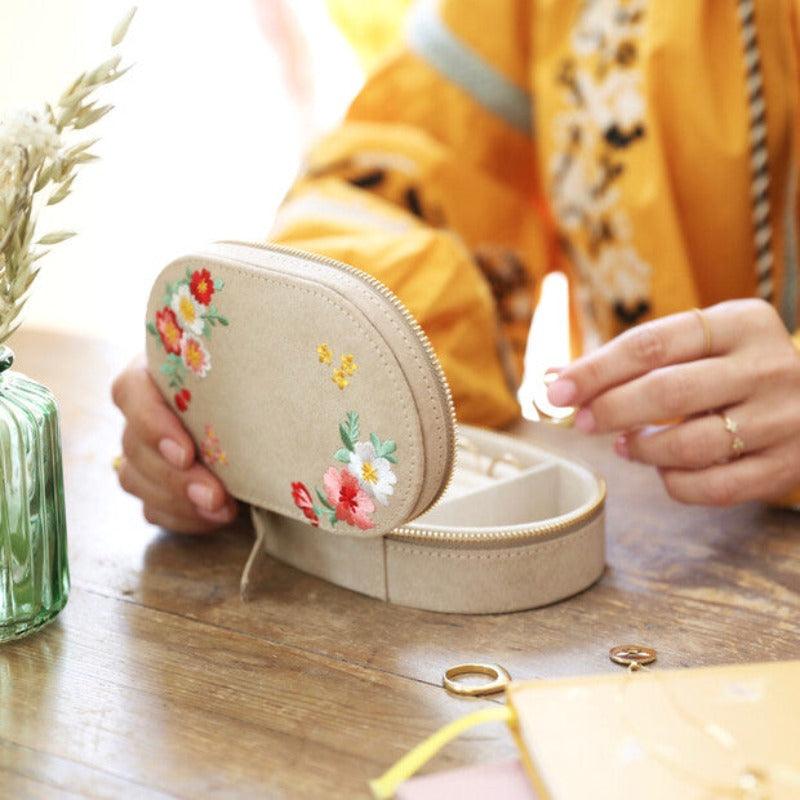 The embroidered box is shown here. There are a range of flowers and leaves decorating the top with embroidery. 