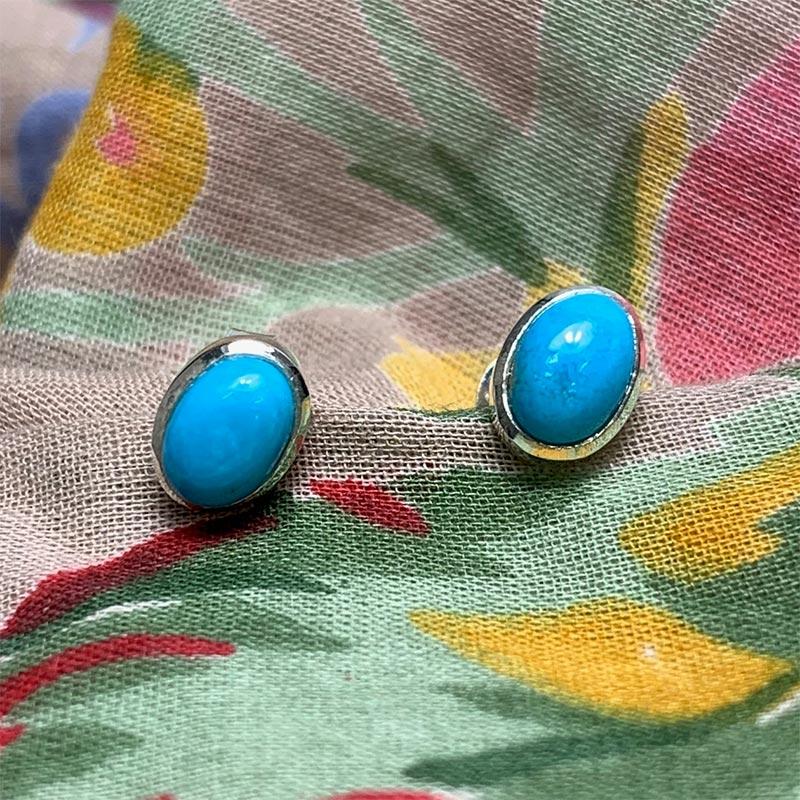 Closeup Jane Austen Turquoise Earrings on a colourful cloth