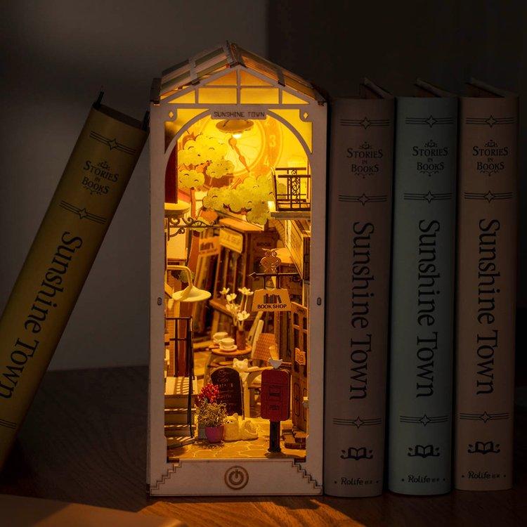 here you can see the book nook lit up in a dark room. It looks very cosy with the lights on and a warm hue is cast over the tiny town within the book nook. 
