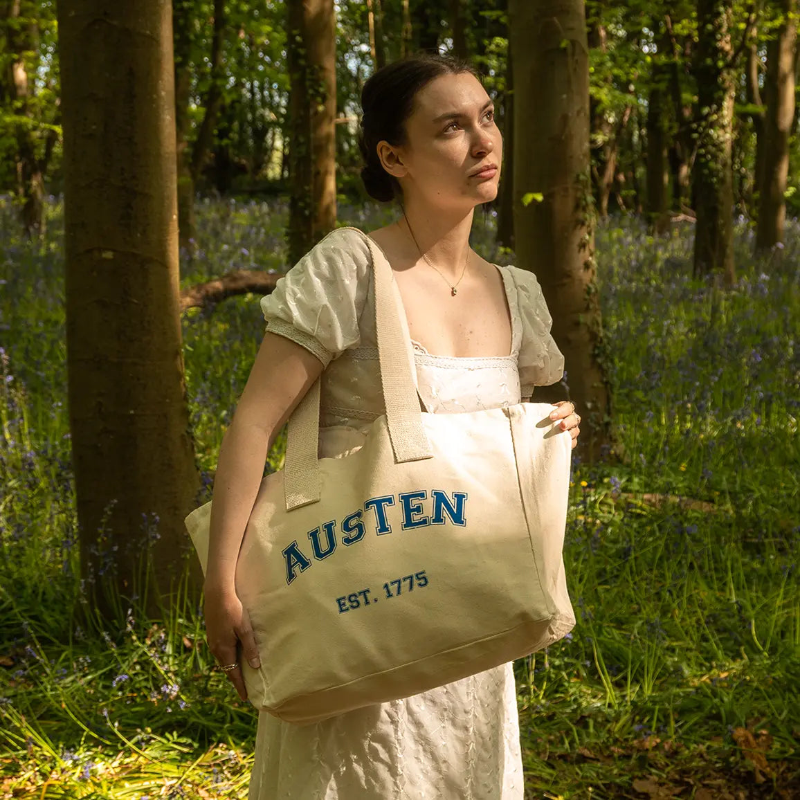 A woman in a forest with a Jane Austen tote bag