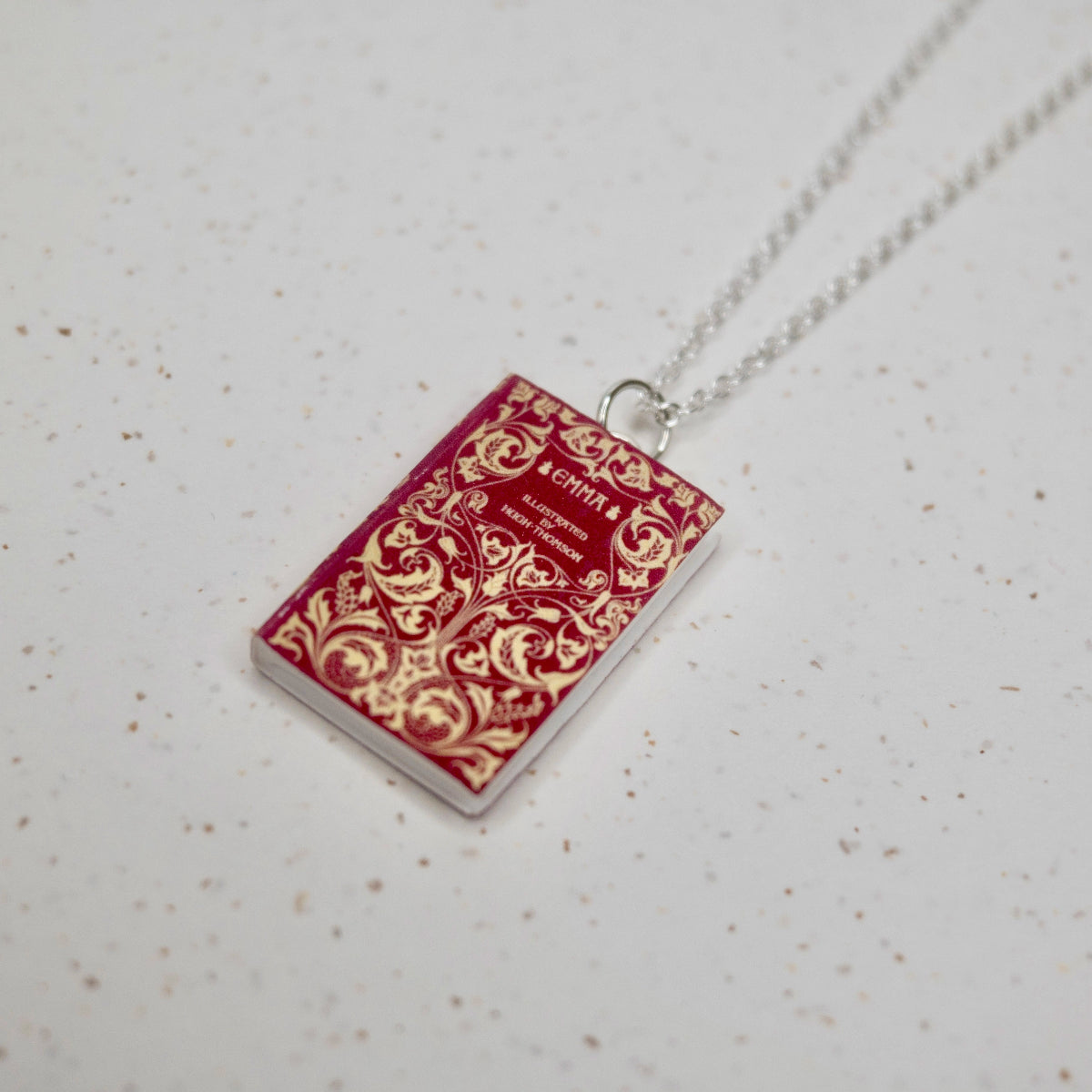 Emma book necklace n a speckled, white background.