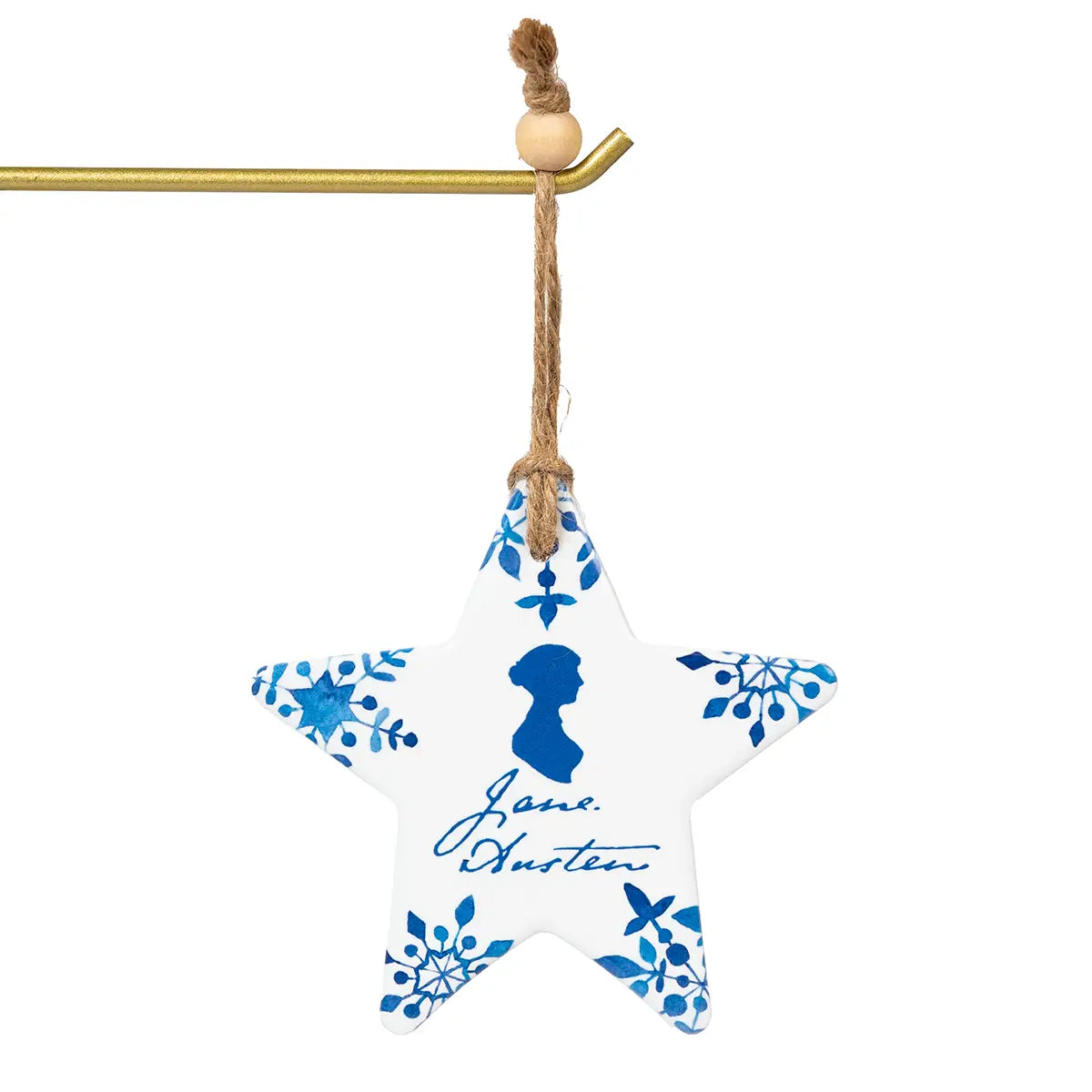 White and blue star shaped ceramic christmas decoration featuring Jane Austen's profile and signature, hanging from a gold rod by a rough string