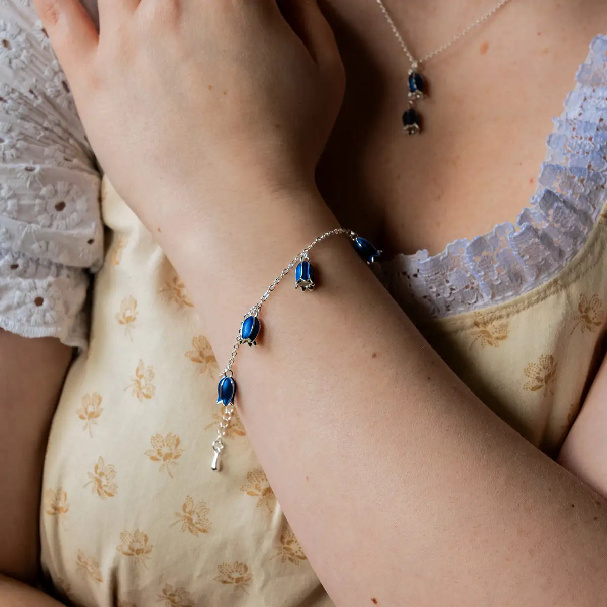 Model wearing the bluebell bracelet on her wrist, with the bluebell necklace in the background