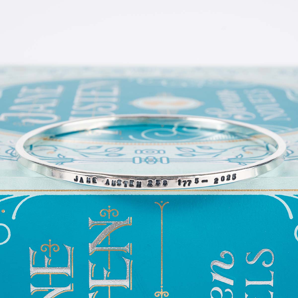 Silver Jane Austen 250th Anniversary bangle bracelet engraved with 'Jane Austen 250 1775-2025' on a book.