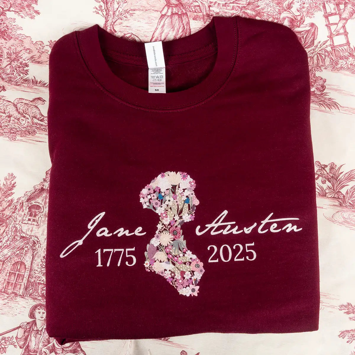 Maroon sweatshirt with floral design and text on a patterned background