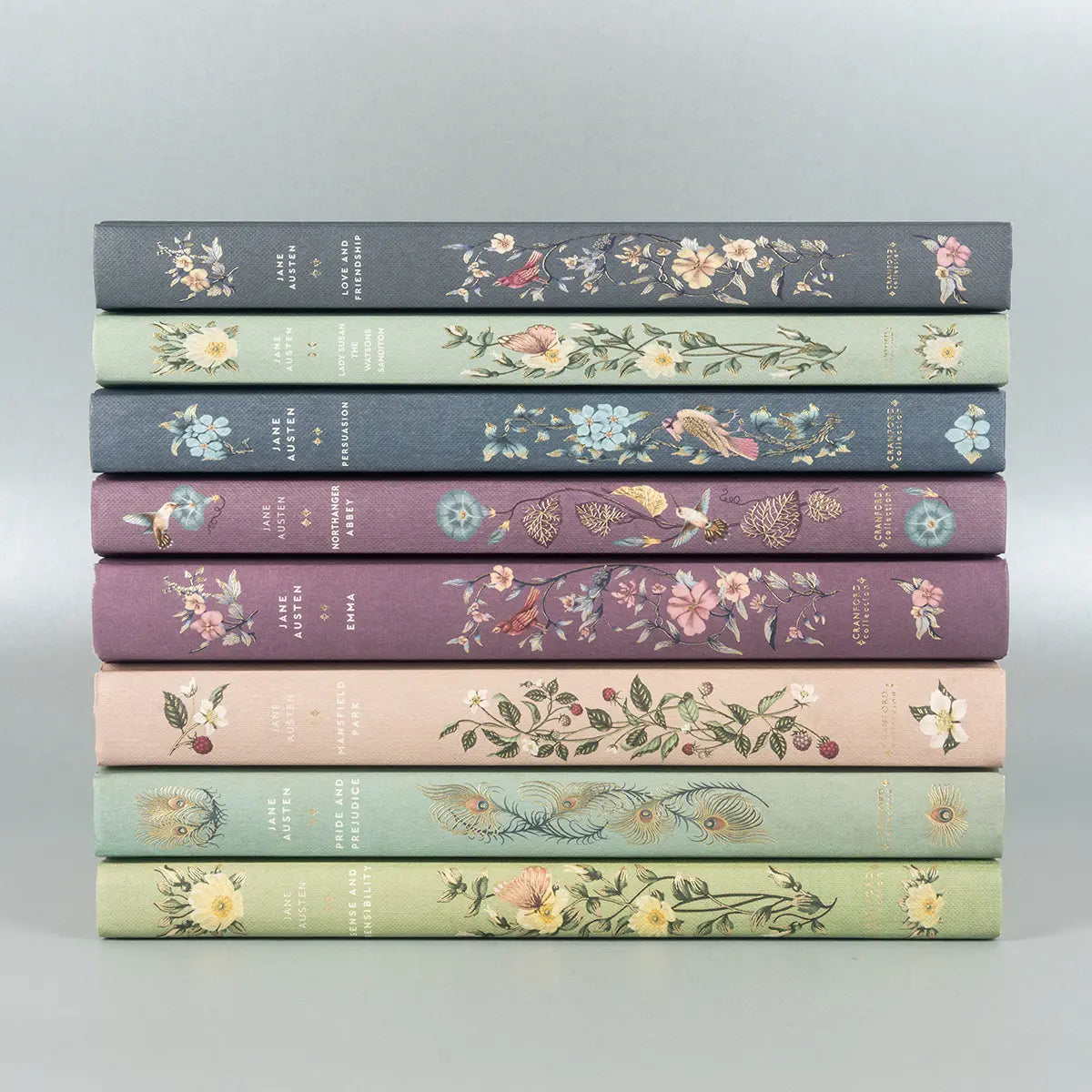 Eight of Jane Austen's Hardback Editions in a stack. Spines decorated with colour, plants and flowers, birds and butterflies.