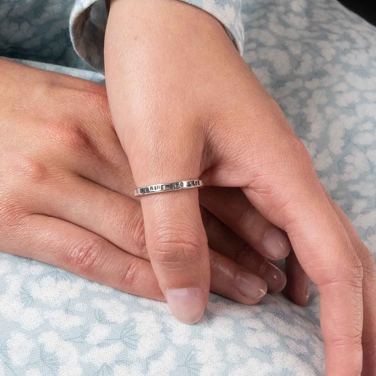 Ring engraved with 'I admire and love you'. Hands crossed over a regency dress.
