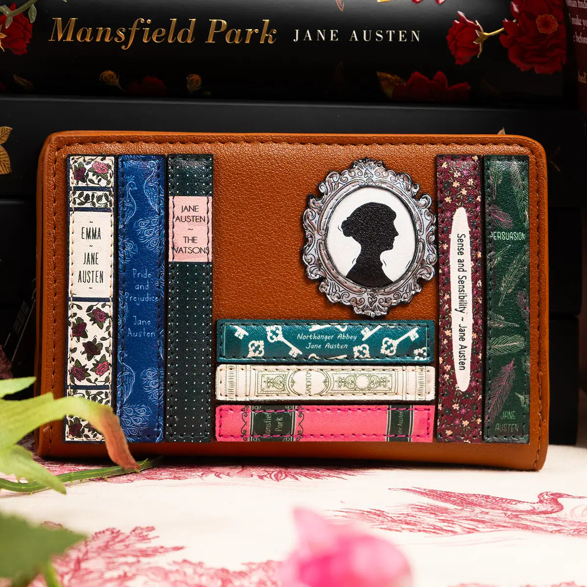 Brown faux leather Jane Austen themed flap over purse with books behind and plants in the foreground