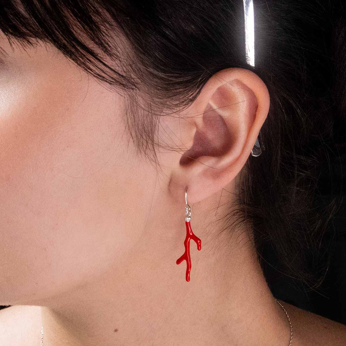 Coral earring with silver hook in a model's ear.