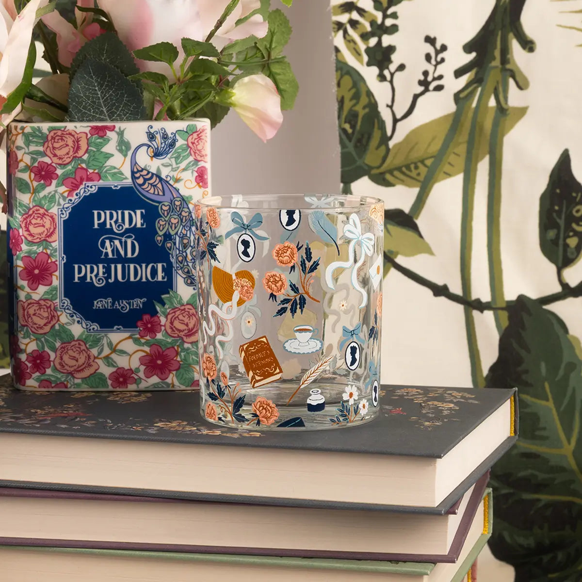 a jane austen themed tumbler on a stack of books with props and a forest themed background
