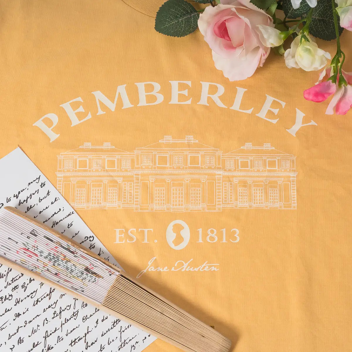 A Jane Austen Pemberley T-Shirt in yellow with a note, fan, and flowers