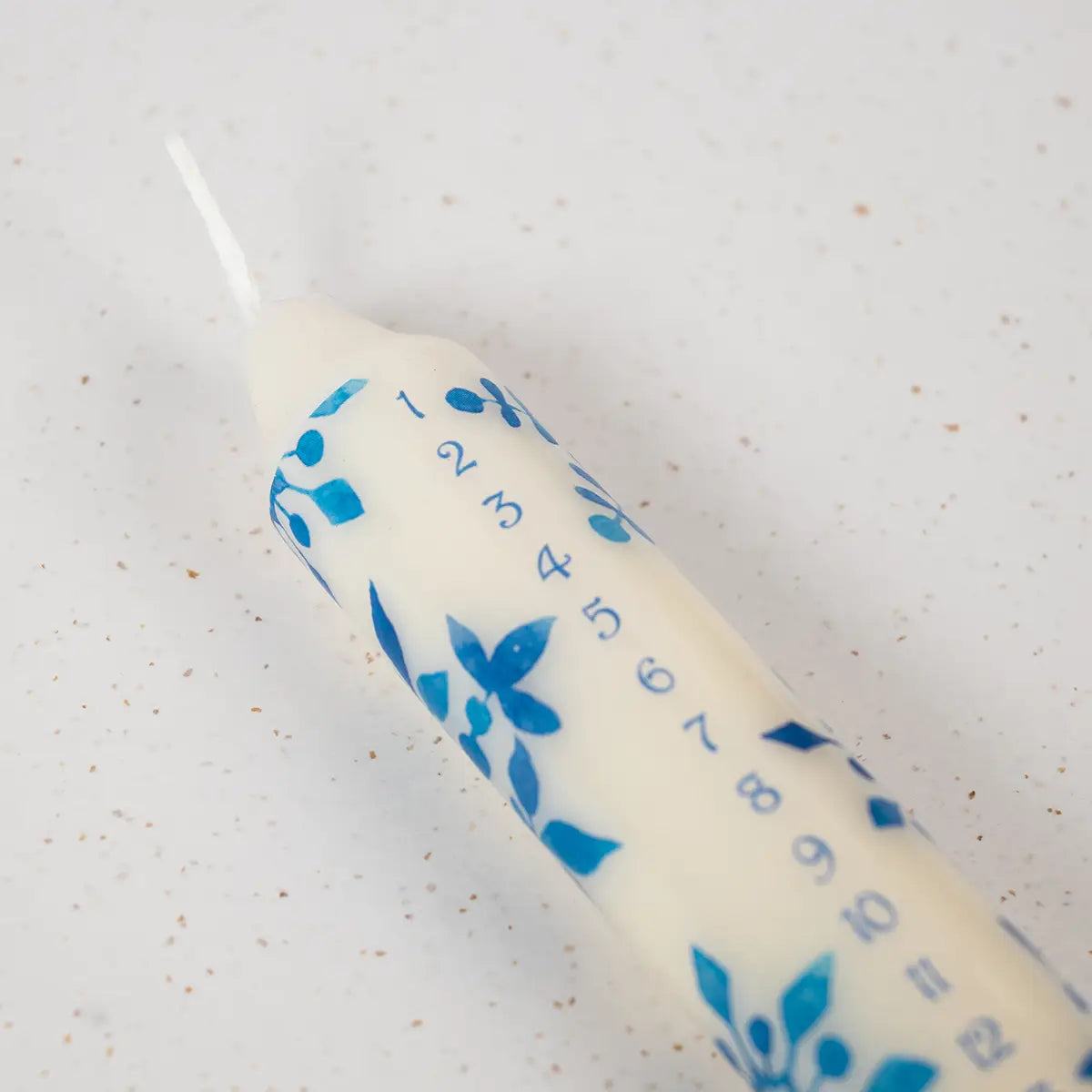 A white advent candle with blue details on a speckled background