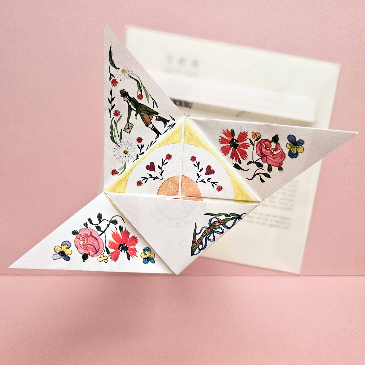Decorative folded paper with floral designs on a pink background