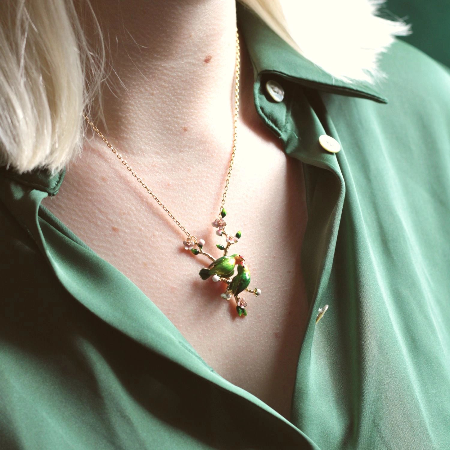 Close up of lovebird pendant necklace on a models neck