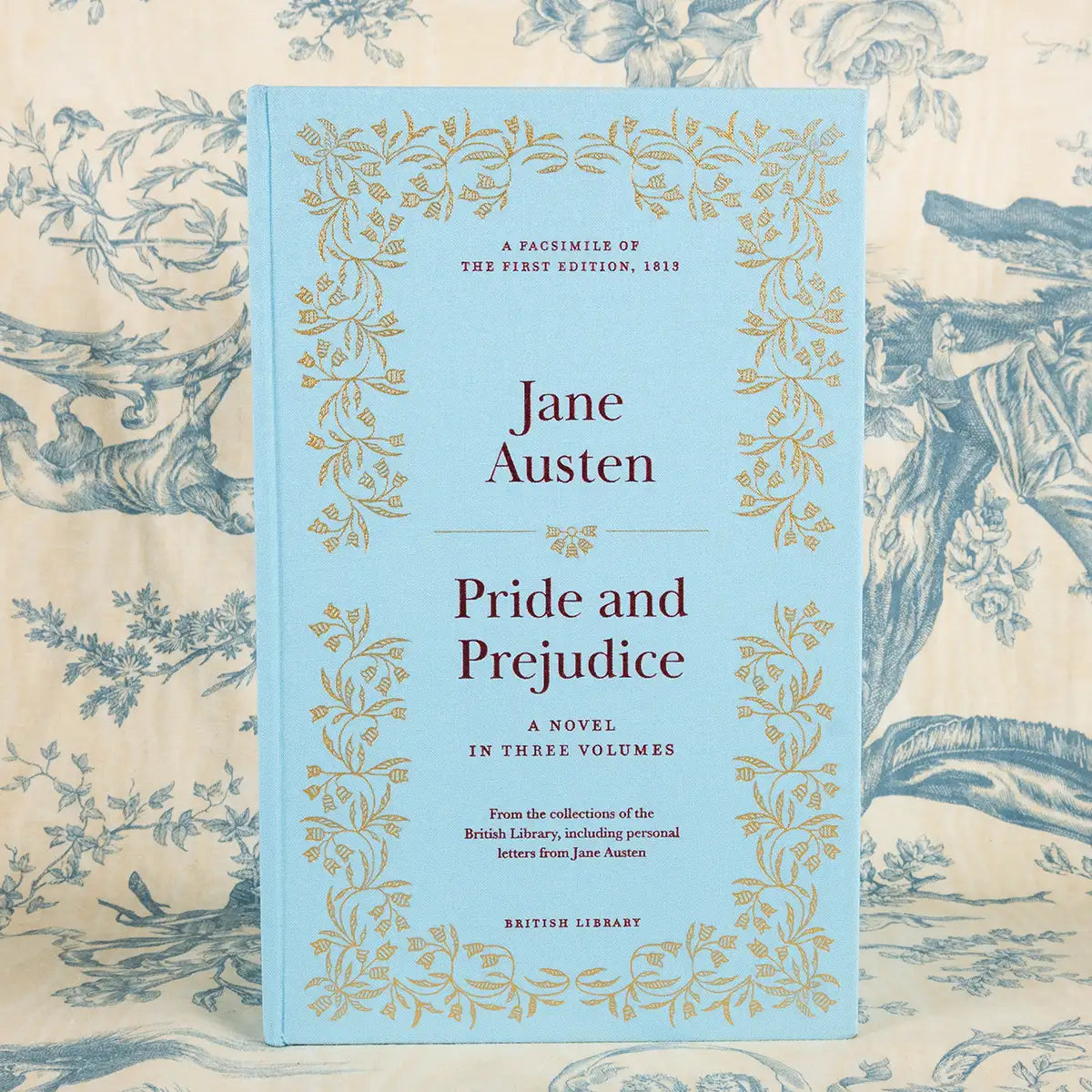 Book cover of 'Pride and Prejudice' by Jane Austen on a decorative background. The box is a pale blue with gold embellishments and floral decorations.