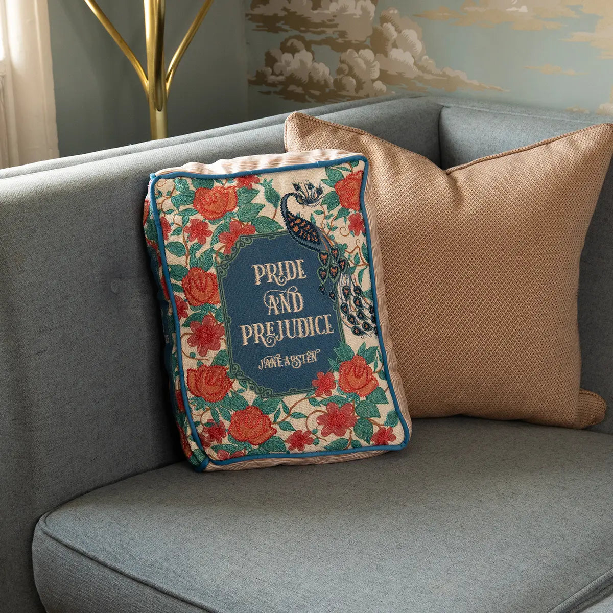 A pride and prejudice themed book cover style cushion on a blue couch