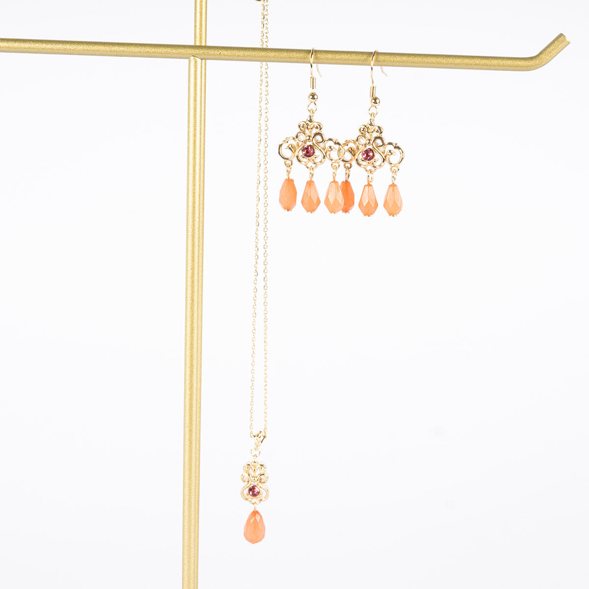 Regency Coral Drop Earrings and Necklace hanging from a golden jewellery stand