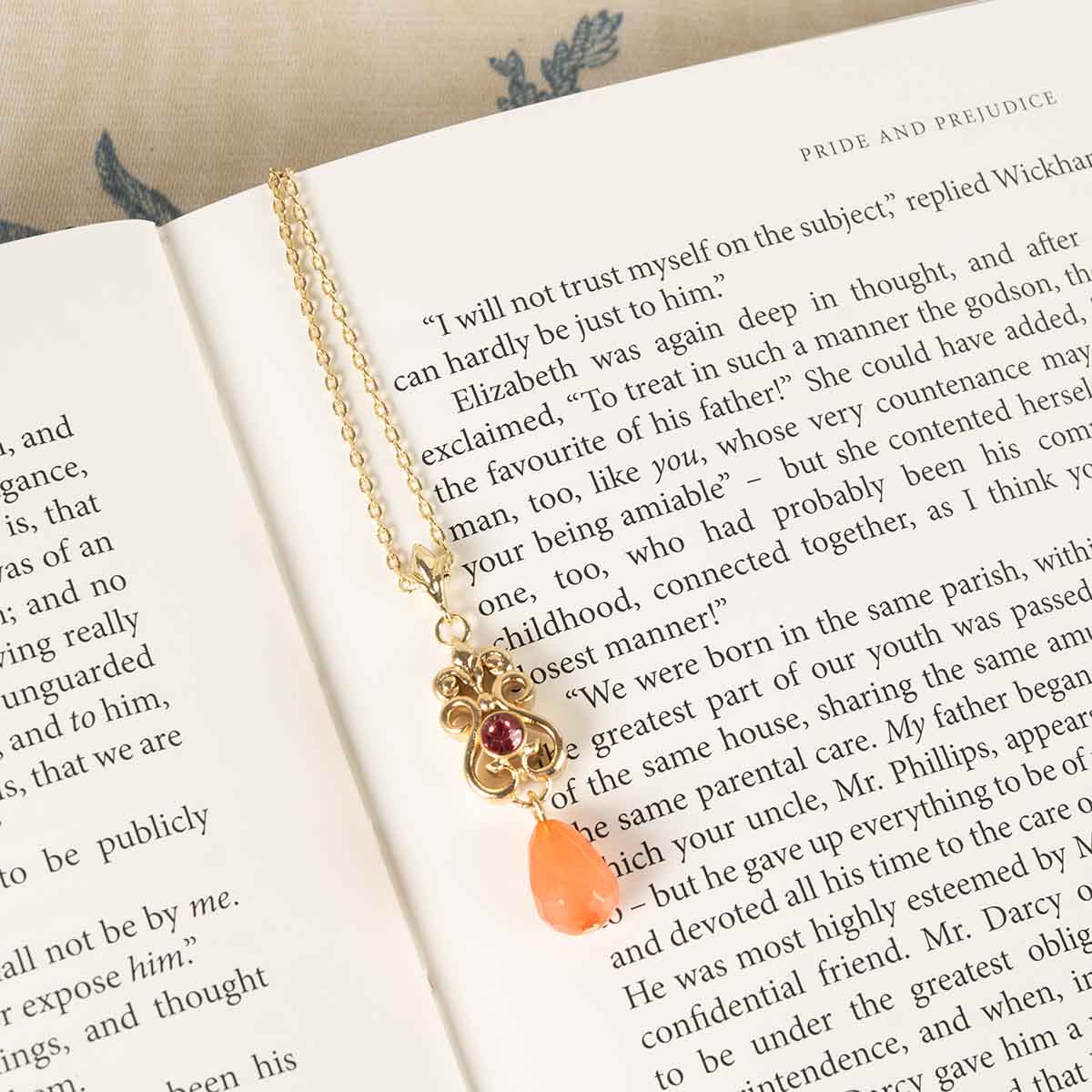 Regency Coral Necklace resting on book pages.