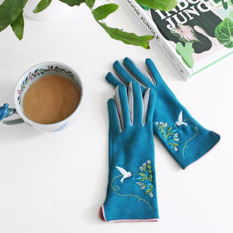 Teal-coloured gloves with embroidered flowers and bird details.
