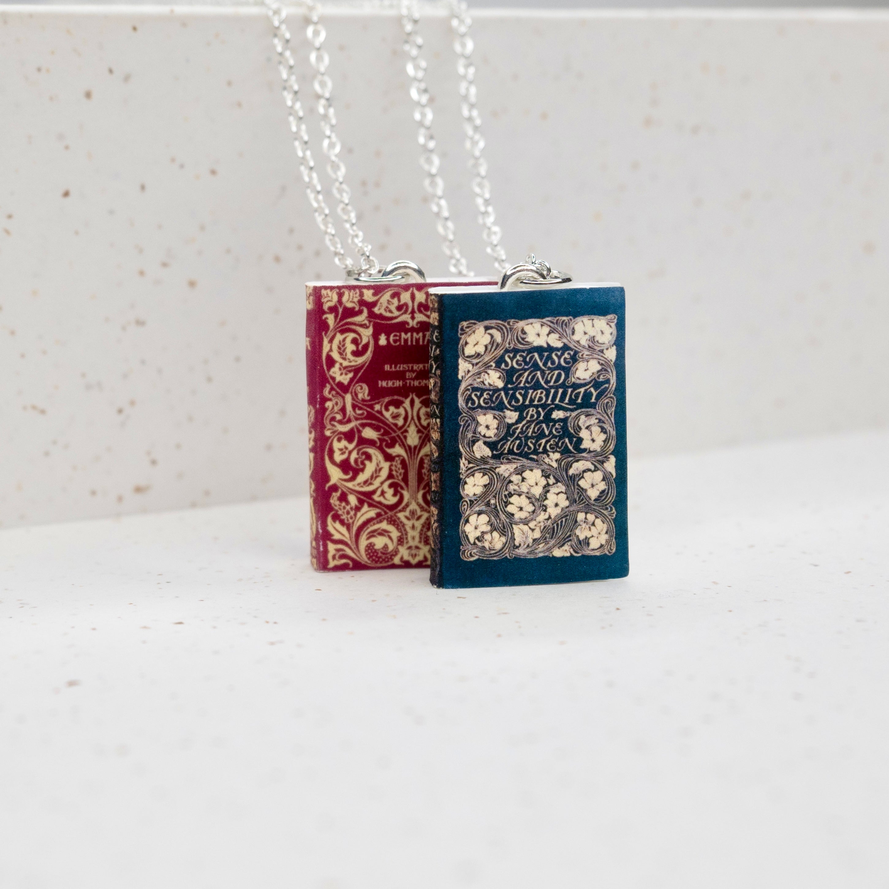 Sense & Sensibility and Emma Necklaces in blue and red standing upright