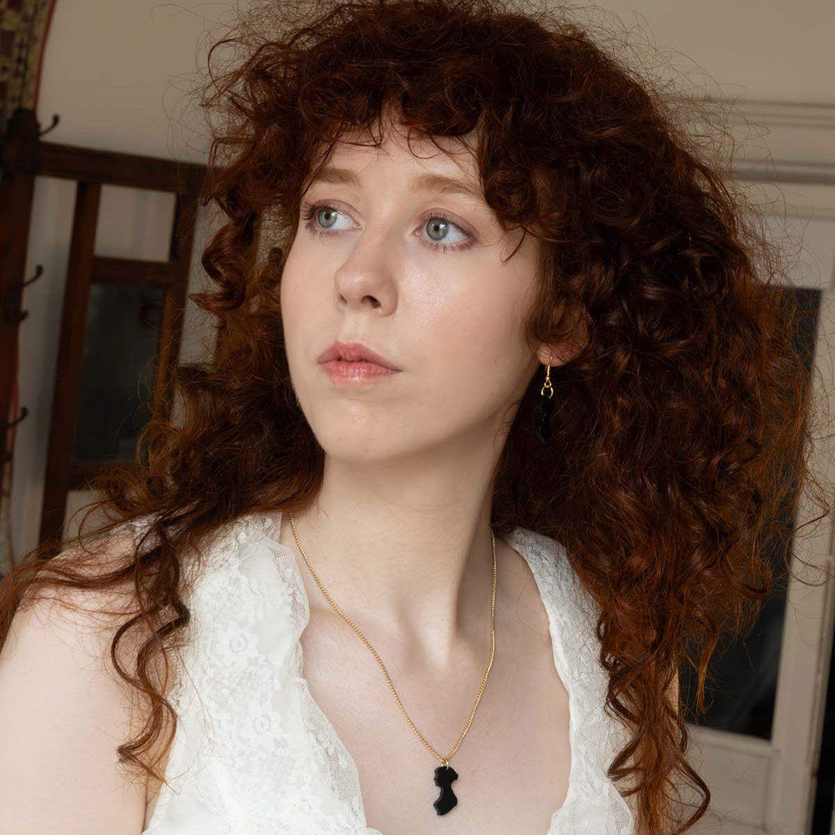 Black acrylic earrings in the shape of Jane Austen's silhouette on a woman's ear