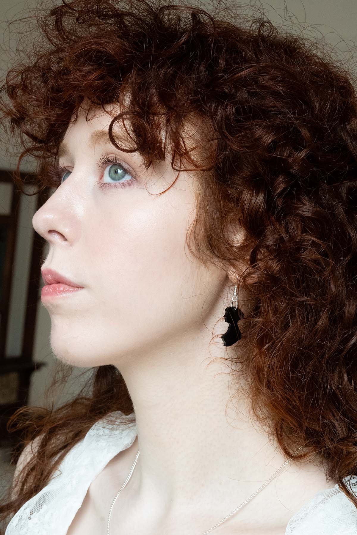 Black acrylic earrings in the shape of Jane Austen's silhouette on a womans ear