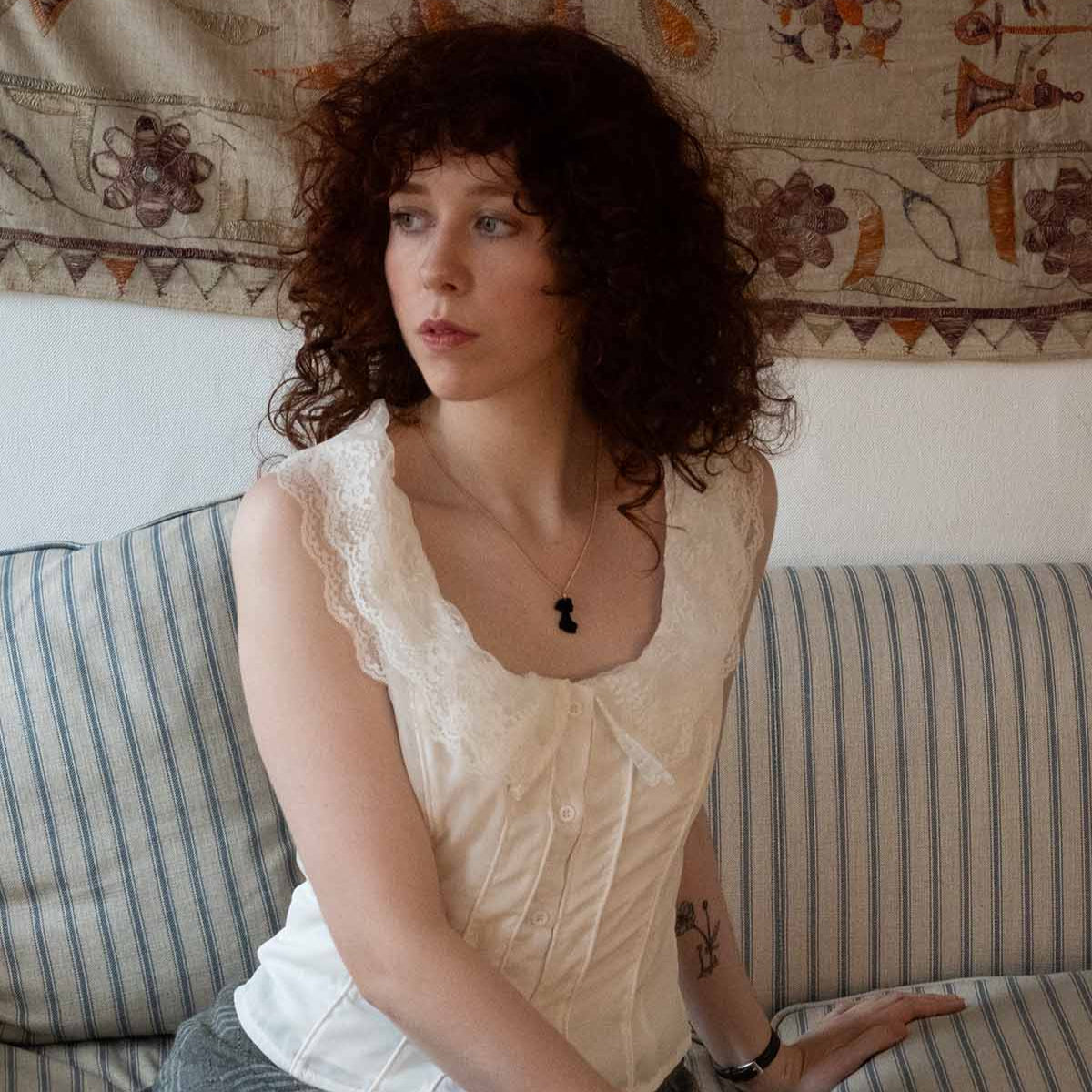 Black acrylic necklace on a gold chain on the neck of a woman in the shape of Jane Austen's silhouette