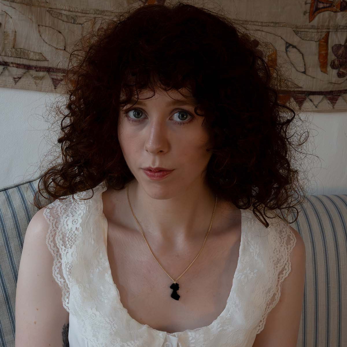 Black acrylic necklace on a gold chain on the neck of a woman in the shape of Jane Austen's silhouette