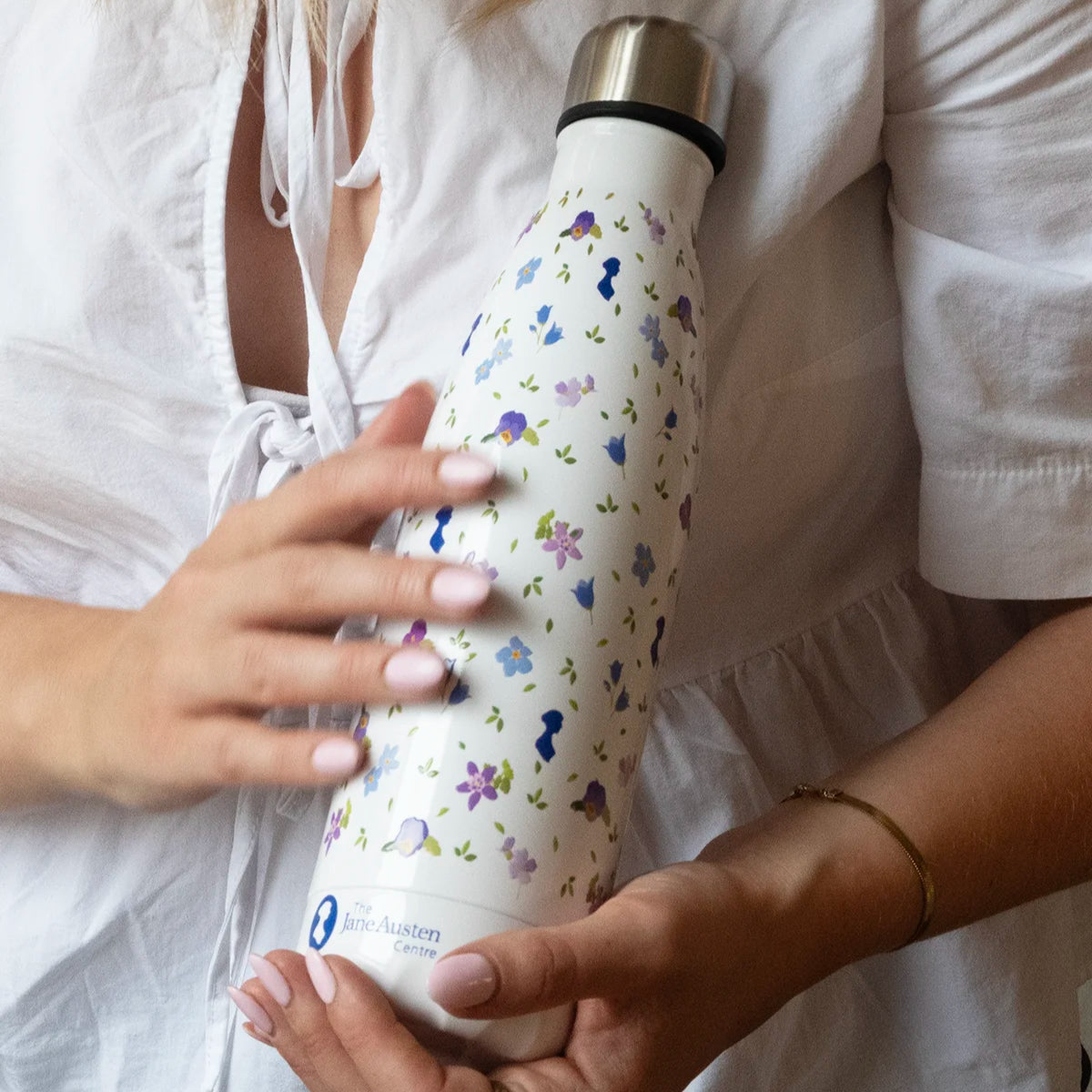 Close up Water Bottle with Floral designs and Jane Austen silhouette being held by woman