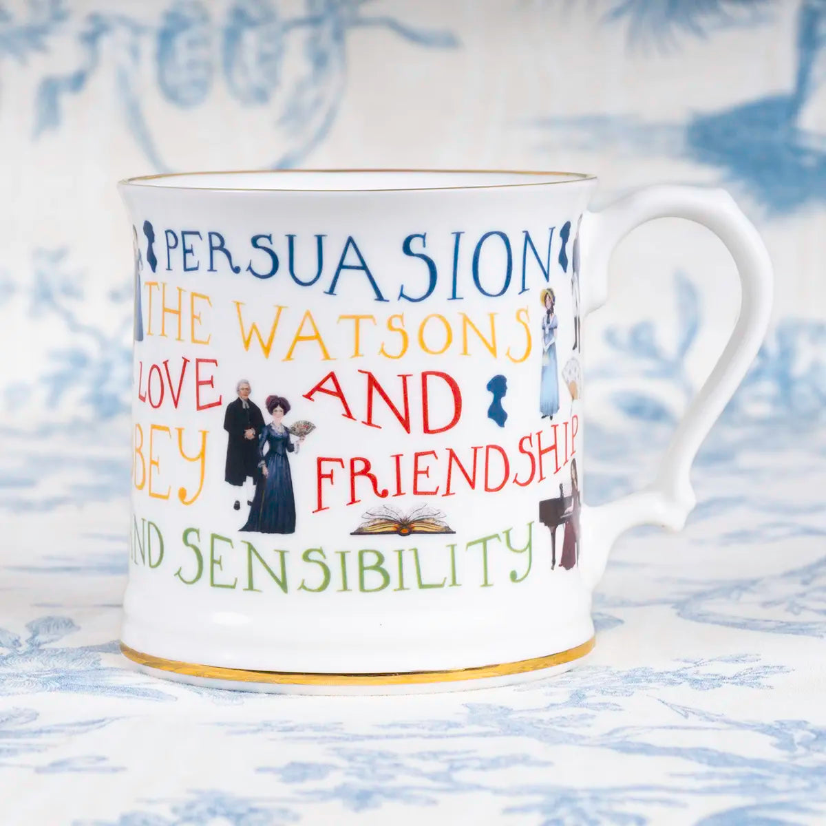 A mug with Jane Austen themed text and illustration with gold trim against a blue background