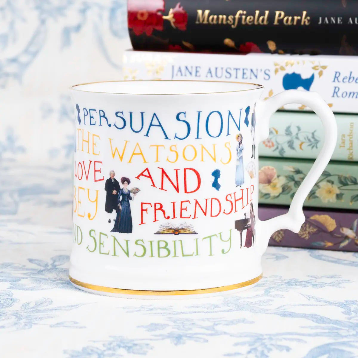 limited edition mug featuring the titles of Jane Austen's novels in front of a stack of Jane Austen's books